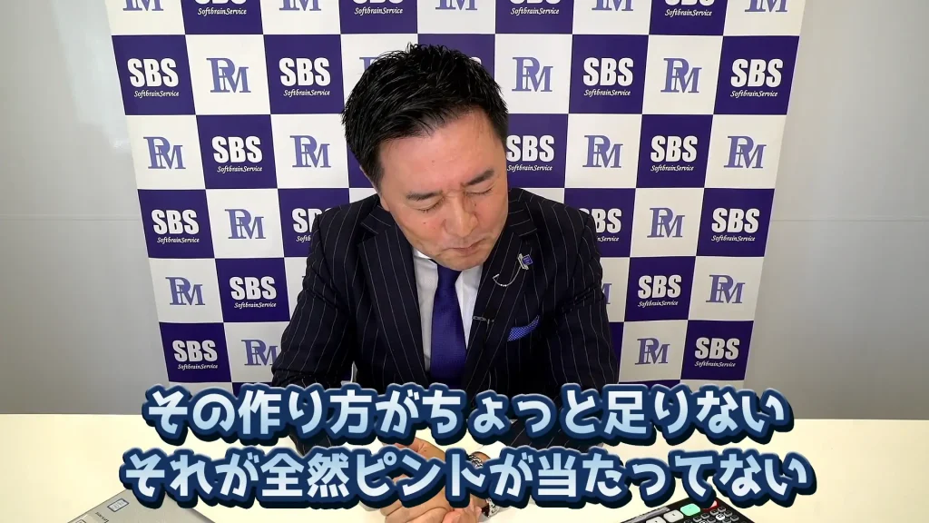 ビジネススーツを着た男性が机に座る。彼の後ろには「SBS」と「PM」のロゴが入った市松模様の背景があります。画像の下部にある日本語のテキストは「その作り方がちょっと足りないそれが全部ピンといてない」とあり、彼が競に勝つための競争戦略を熟考している可能性があることを示唆している。